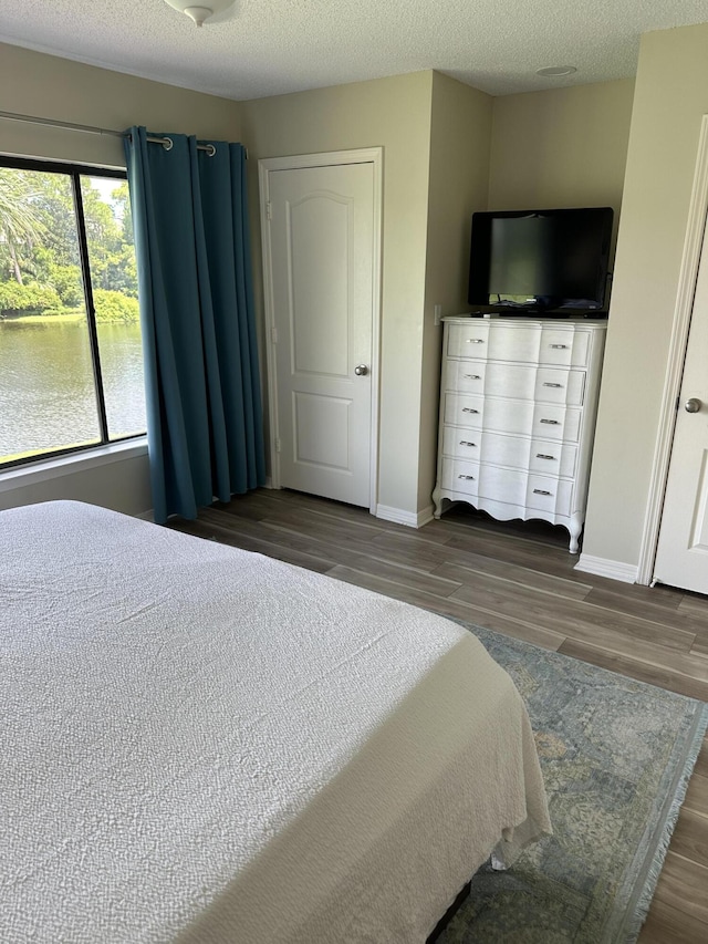 bedroom with dark hardwood / wood-style flooring, multiple windows, and a textured ceiling