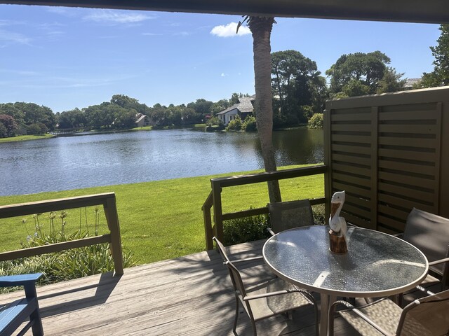 wooden terrace with a water view and a lawn