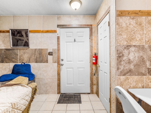 interior space with tile patterned flooring, tile walls, and a textured ceiling