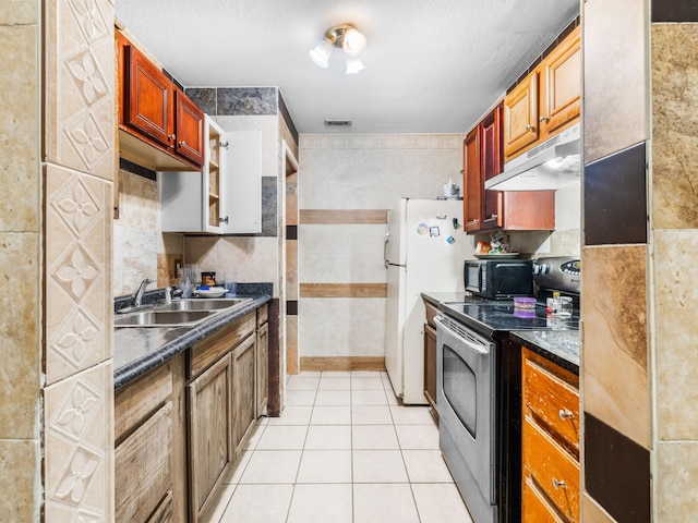 kitchen with sink, tile walls, a textured ceiling, light tile patterned flooring, and stainless steel range with electric cooktop