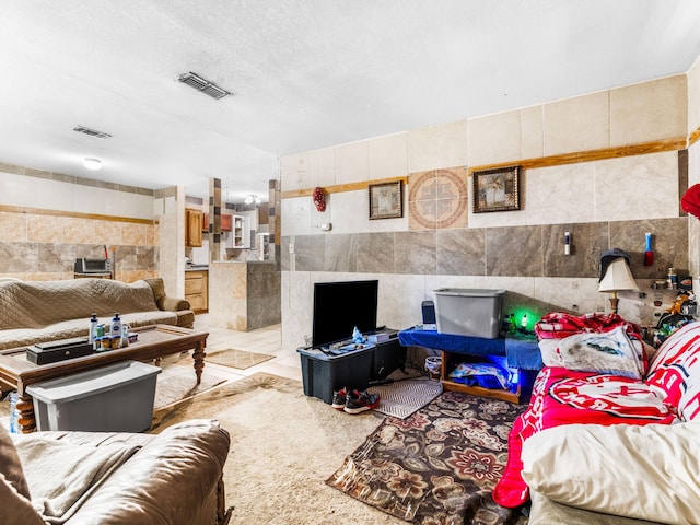 living room with a textured ceiling and tile walls