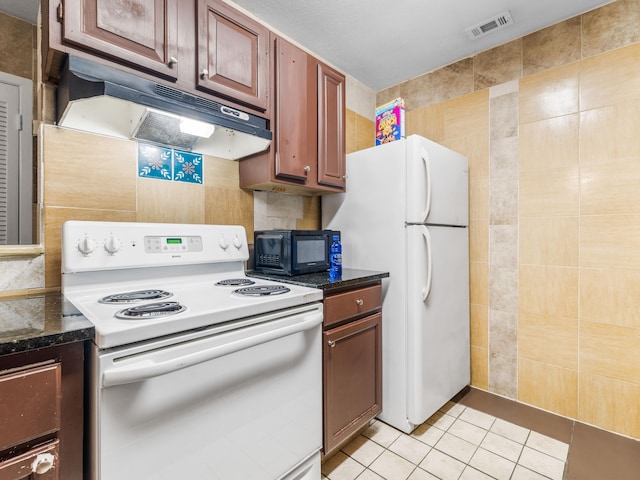 kitchen with light tile patterned floors, tile walls, and white appliances