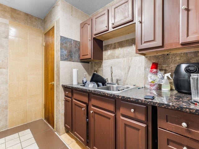 kitchen with light tile patterned flooring, sink, tile walls, and backsplash