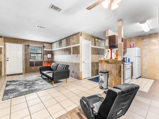 tiled living room with tile walls and ceiling fan