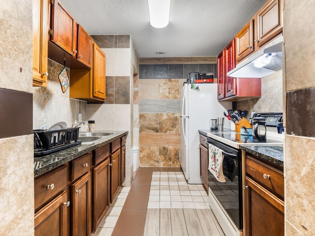 kitchen featuring light tile patterned floors, a textured ceiling, tile walls, electric range oven, and sink