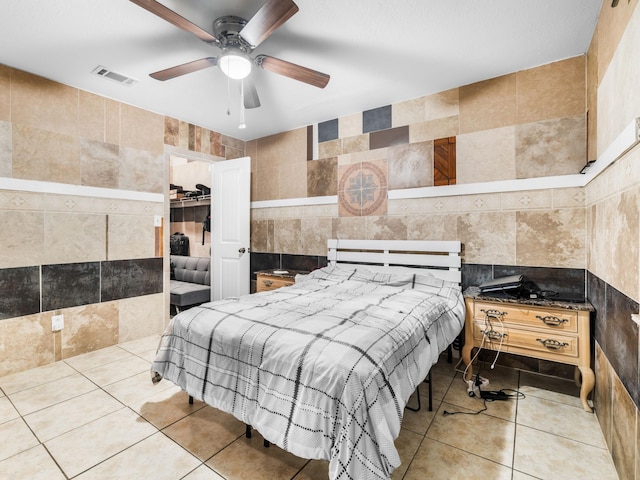 tiled bedroom with ceiling fan and tile walls