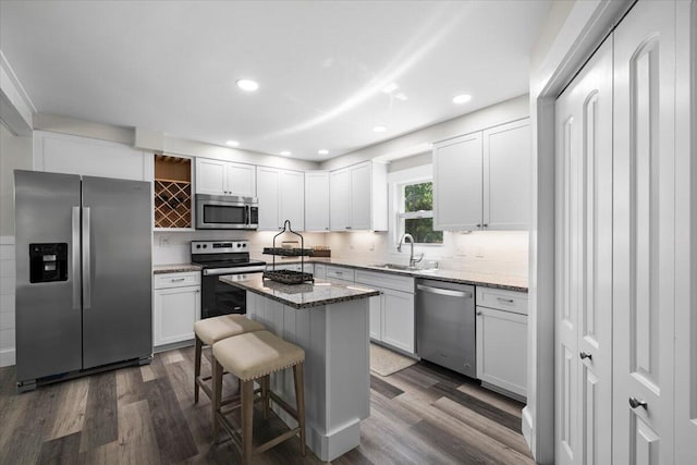 kitchen with white cabinetry, light stone countertops, stainless steel appliances, and a kitchen island