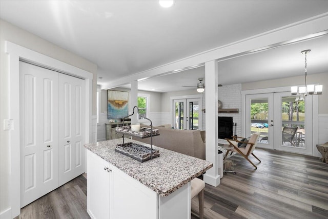 kitchen featuring dark wood-type flooring, hanging light fixtures, light stone countertops, white cabinets, and french doors