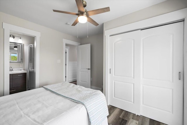 bedroom featuring dark wood-type flooring, connected bathroom, ceiling fan, and a closet