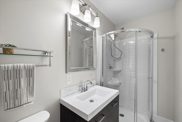 bathroom featuring vanity, toilet, and a shower with shower door