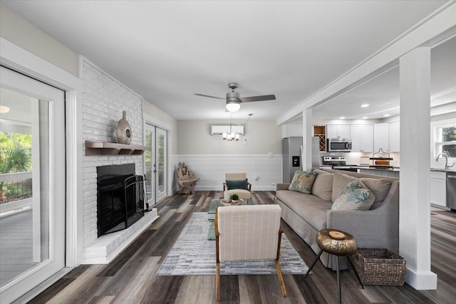 living room featuring a fireplace, sink, a wall mounted AC, ceiling fan, and dark wood-type flooring