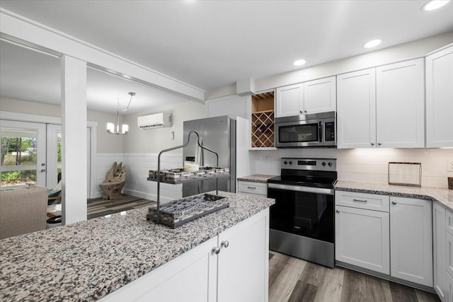 kitchen featuring white cabinetry, pendant lighting, wood-type flooring, and appliances with stainless steel finishes