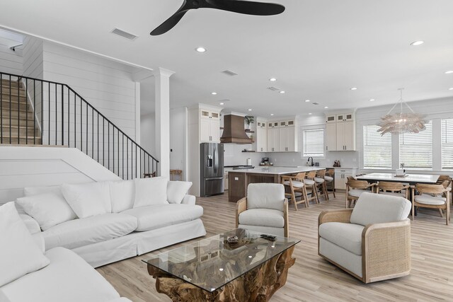 living room featuring sink, light hardwood / wood-style flooring, and ceiling fan with notable chandelier