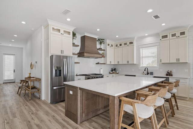 kitchen featuring a kitchen island, light wood-type flooring, custom exhaust hood, and stainless steel refrigerator with ice dispenser