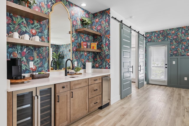 kitchen featuring light wood-type flooring, sink, beverage cooler, and a barn door