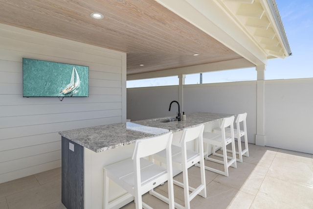 kitchen featuring light tile patterned floors, wooden walls, sink, and wooden ceiling