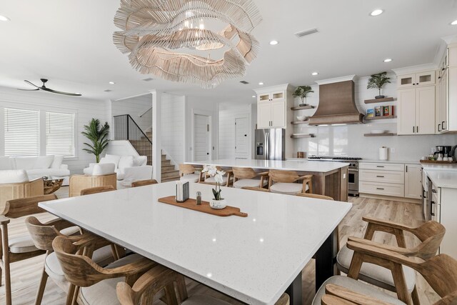 kitchen with white cabinets, a spacious island, stainless steel appliances, and custom range hood