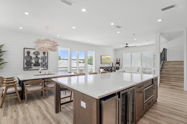 kitchen featuring dark brown cabinets, beverage cooler, light hardwood / wood-style flooring, and a center island