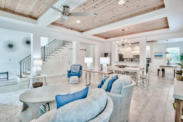 living room featuring ceiling fan with notable chandelier, a raised ceiling, light wood-type flooring, and wooden ceiling