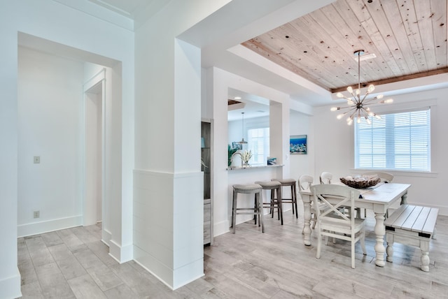 dining area with a notable chandelier, light wood-type flooring, wood ceiling, and a tray ceiling