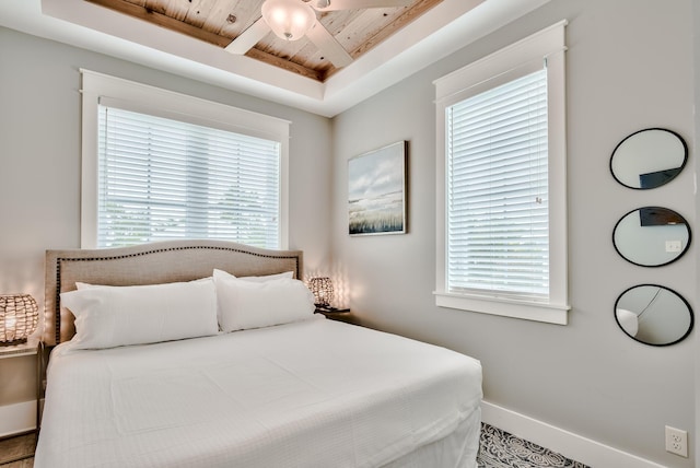 bedroom featuring a tray ceiling, multiple windows, and wooden ceiling