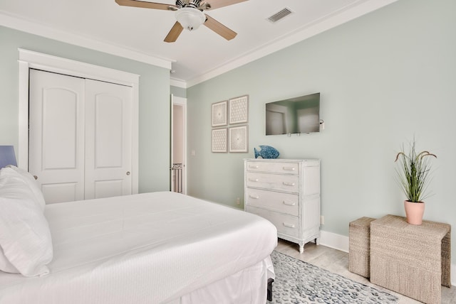 bedroom featuring light wood-type flooring, a closet, ornamental molding, and ceiling fan