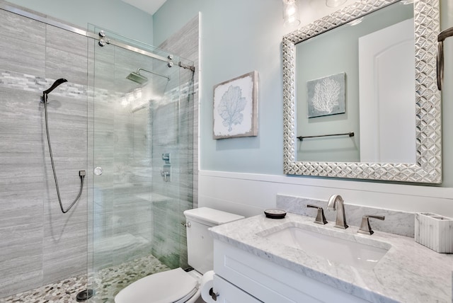 bathroom featuring vanity, toilet, and a shower with door