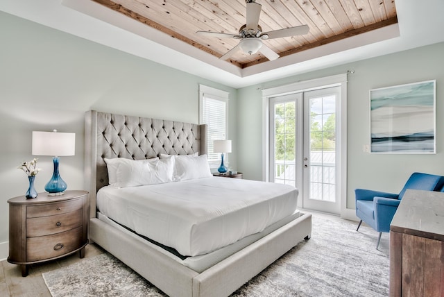 bedroom featuring ceiling fan, french doors, a raised ceiling, access to outside, and light wood-type flooring