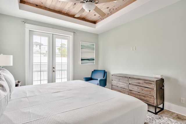 bedroom featuring access to outside, french doors, a tray ceiling, and light hardwood / wood-style flooring