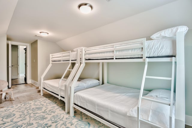 bedroom featuring lofted ceiling and light wood-type flooring