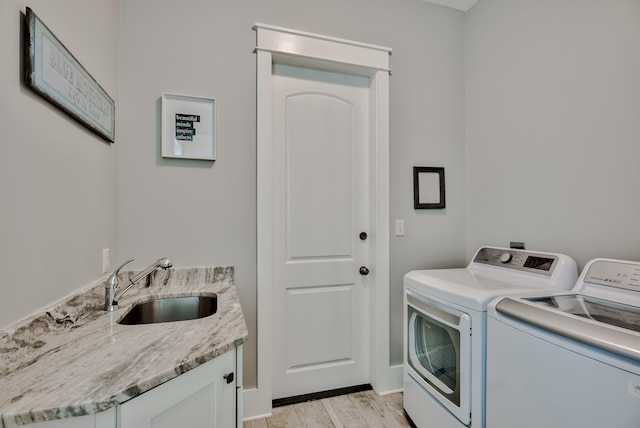 laundry area with cabinets, light wood-type flooring, independent washer and dryer, and sink