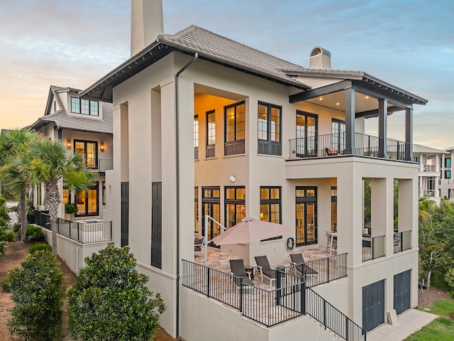 back house at dusk featuring a patio area