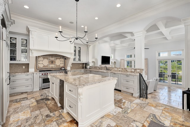 kitchen featuring tasteful backsplash, white cabinets, ceiling fan with notable chandelier, beamed ceiling, and a center island