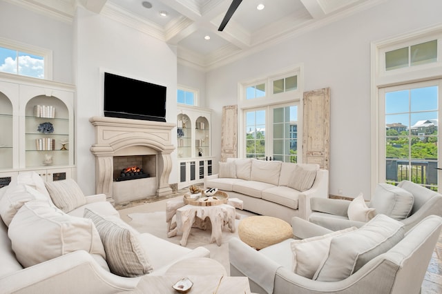 living room with beam ceiling, ceiling fan, coffered ceiling, crown molding, and a towering ceiling