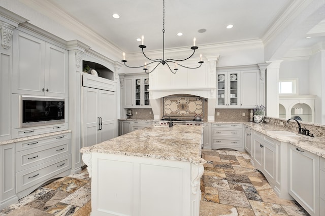 kitchen featuring decorative backsplash, light stone counters, black microwave, decorative light fixtures, and a notable chandelier