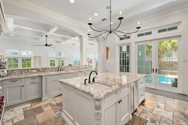 kitchen with a kitchen island with sink, sink, a healthy amount of sunlight, and french doors