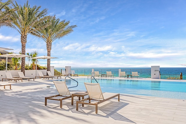 view of pool with a water view and a patio