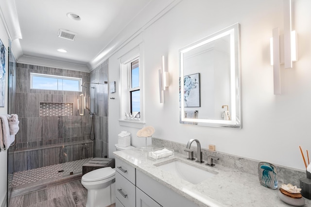 bathroom featuring vanity, tiled shower, ornamental molding, and toilet