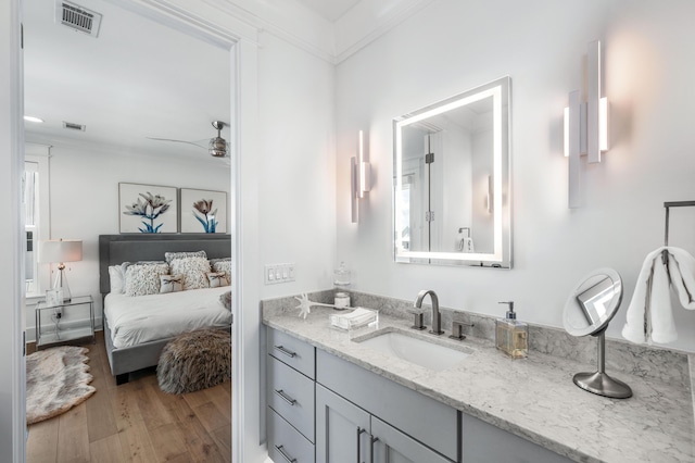 bathroom featuring hardwood / wood-style flooring, ceiling fan, ornamental molding, and vanity