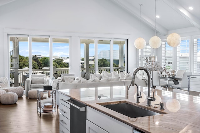 kitchen featuring sink, dark wood-type flooring, white cabinetry, hanging light fixtures, and light stone countertops