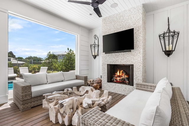 living room featuring ceiling fan, a large fireplace, plenty of natural light, and hardwood / wood-style floors