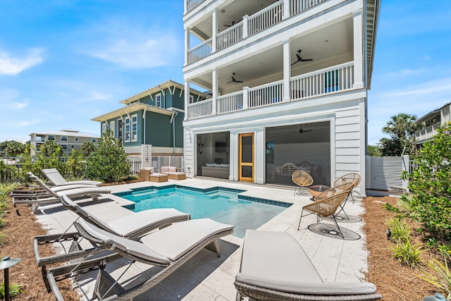 rear view of property featuring a patio, a balcony, outdoor lounge area, ceiling fan, and a fenced in pool