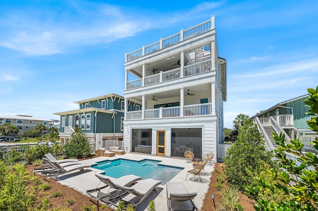 rear view of property featuring a fenced in pool, ceiling fan, a patio, an outdoor living space, and a balcony