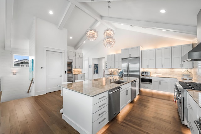 kitchen with pendant lighting, high quality appliances, beamed ceiling, backsplash, and a kitchen island with sink