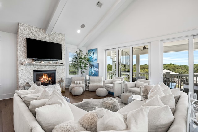 living room featuring dark wood-type flooring, high vaulted ceiling, a large fireplace, ceiling fan, and beam ceiling