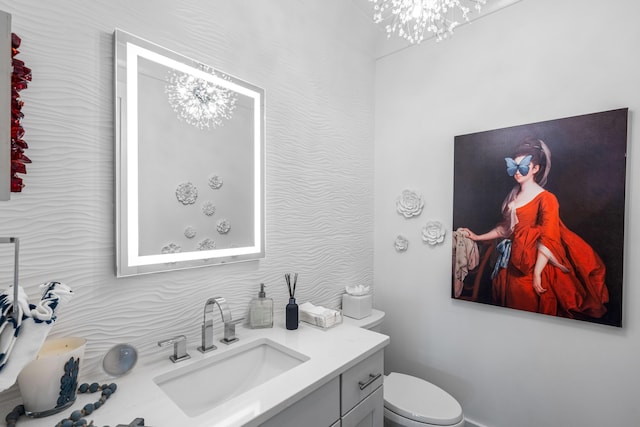 bathroom featuring vanity, a chandelier, and toilet