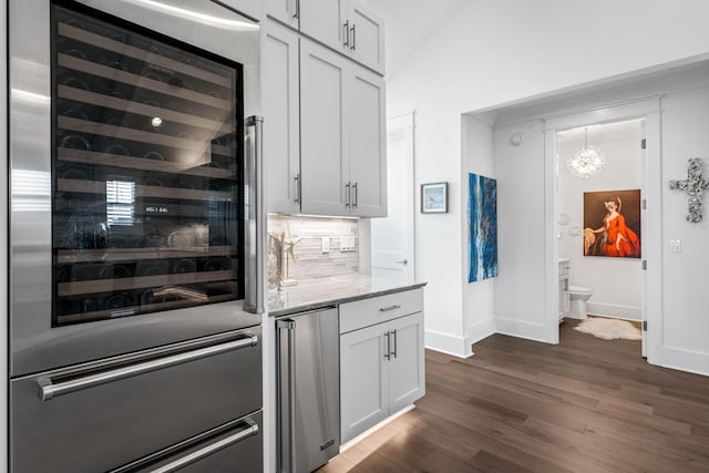 kitchen with white cabinets, beverage cooler, dark hardwood / wood-style flooring, decorative backsplash, and light stone countertops