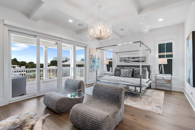 bedroom with hardwood / wood-style flooring, multiple windows, access to exterior, and beam ceiling