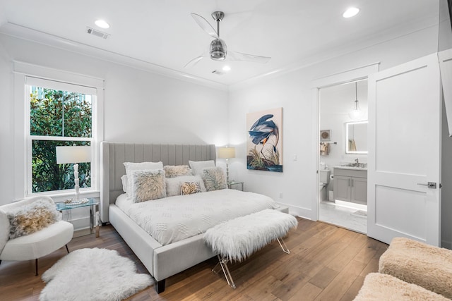 bedroom featuring sink, hardwood / wood-style flooring, ceiling fan, crown molding, and ensuite bath