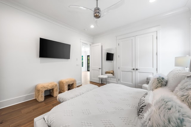 bedroom featuring dark hardwood / wood-style flooring, crown molding, ceiling fan, and a closet